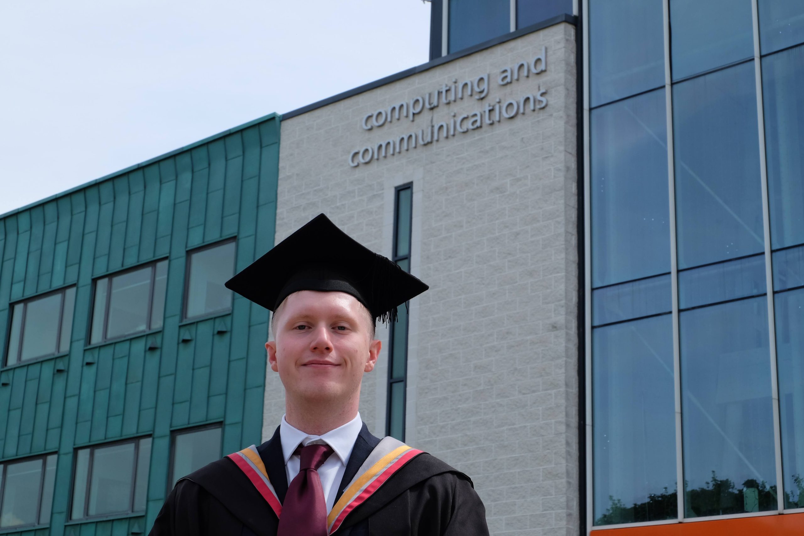 Picture of Luke Halpin in graduation attire outside Lancaster University School of Computing and Communications